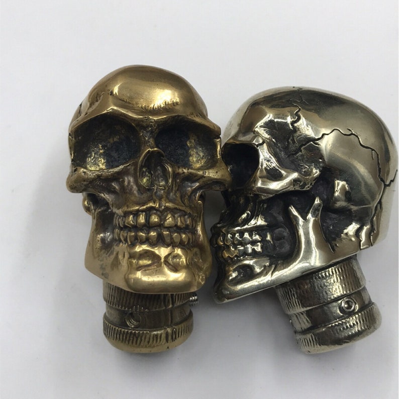May include: Two decorative skull-shaped bottle stoppers. One is gold and the other is silver.