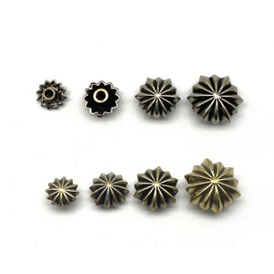 May include: Assortment of silver and gold star-shaped metal studs with a raised centre. The studs are various sizes.