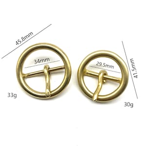 May include: Two gold-toned metal belt buckles. The larger buckle measures 45.8 mm in diameter and weighs 33 grams. The smaller buckle measures 41.5 mm in diameter and weighs 30 grams.