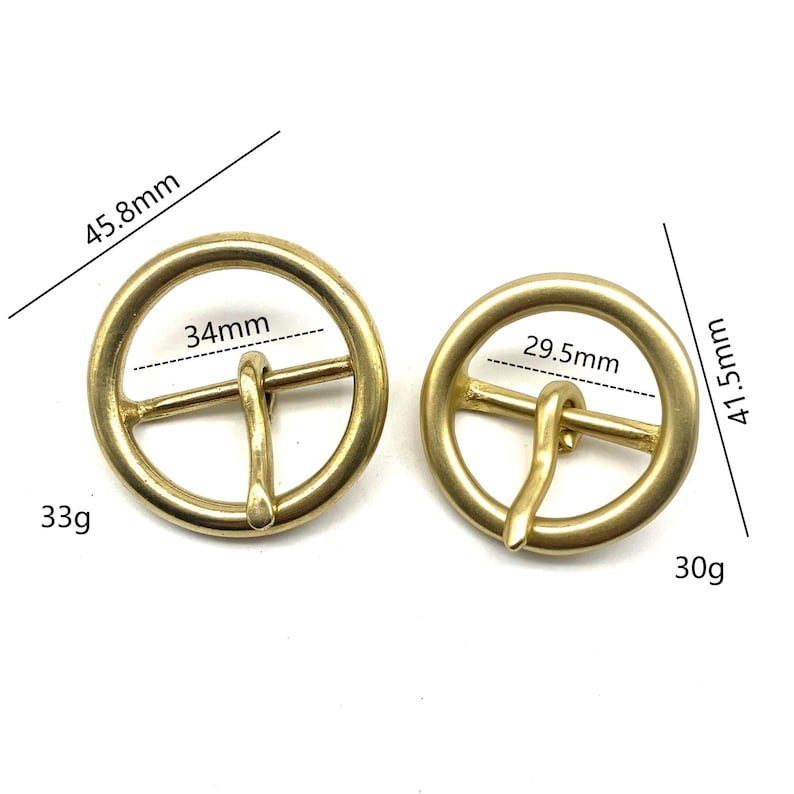 May include: Two gold-toned metal belt buckles. The larger buckle measures 45.8 mm in diameter and weighs 33 grams. The smaller buckle measures 41.5 mm in diameter and weighs 30 grams.