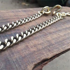 May include: A gold chain with a hook clasp. The chain is made of thick, interlocking links.