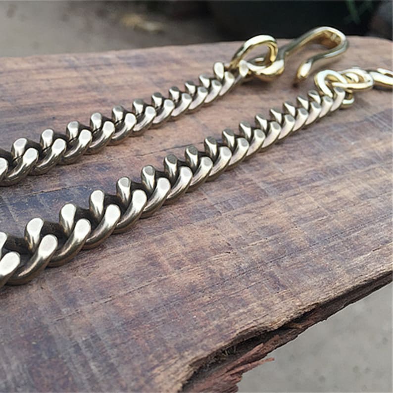 May include: A gold chain with a hook clasp. The chain is made of thick, interlocking links.