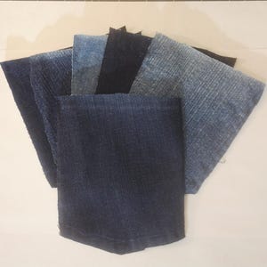 May include: Assortment of denim fabric swatches in various shades of blue and black. The swatches are arranged in a fan shape, showcasing different textures and washes of the denim material. The fabrics are likely for crafting or design purposes.