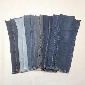 May include: A collection of denim jeans in various shades of blue, arranged side by side. The jeans range from light to dark washes, showcasing a variety of denim styles and colors. The arrangement highlights the different tones and textures of the fabric.