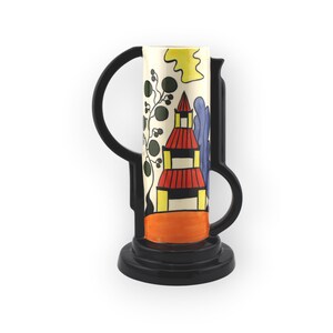 Könnte beinhalten: Eine Keramikvase mit einem zylindrischen, cremefarbenen Körper, der eine bemalte Struktur mit rotem Dach, gelben Akzenten und dunkelgrünem Blattwerk zeigt. Die Vase wird von einem glänzend schwarzen Griff und Sockel eingerahmt, was eine geometrische Silhouette ergibt.