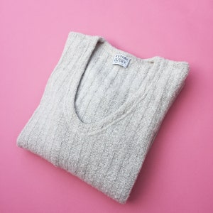 May include: A folded gray sweater with a white label that reads "FUTURE OZBEK" on a pink background.