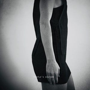 Könnte beinhalten: Schwarzes ärmelloses Kleid mit minimalistischem Design. Das Kleid hat eine klare Silhouette und einen knielangen Saum. Der Text "PEOPLE'S COUTURE" ist unten im Bild aufgedruckt.