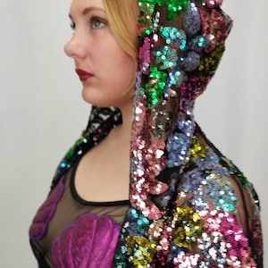 May include: A black mesh top with a purple seashell design and a multi-coloured sequined jacket with a hood.