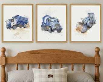 May include: Three framed watercolor art prints featuring construction vehicles. The left print shows a blue dump truck, the center print depicts a blue cement mixer, and the right print displays a blue bulldozer, all set against a white background.