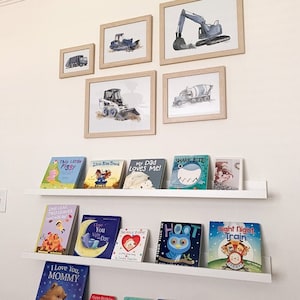 Customer photo of 5 construction truck prints in varying sizes 5x7 to 11 x 14 displayed on boy's bedroom wall