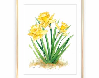 May include: A watercolor painting of three yellow daffodils with green stems and leaves, set in a thin gold-colored frame. The flowers are depicted against a white background with a small patch of light brown earth at the base of the stems.