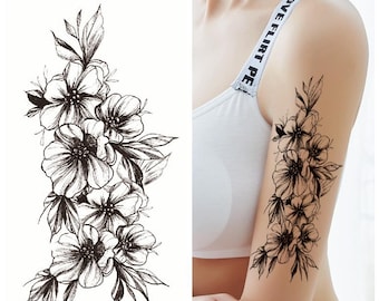 Puede incluir: Tatuaje temporal en blanco y negro con un diseño floral con flores y hojas delicadas.