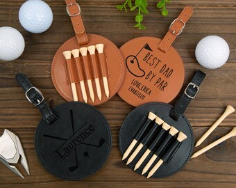 May include: Four brown and black leather luggage tags with golf-themed designs. Two tags have a golf tee holder and the other two have a golf club design. One tag says "Best Dad by Par" with the text "Love, Erica Evabelle" underneath. Another tag says "Laurence".
