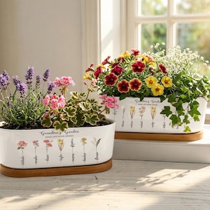 May include: Two white ceramic rectangular planters filled with colorful flowers. One contains lavender and pink flowers, the other has red, yellow, and white blooms. Both planters have a wooden base and the text "Grandma's Garden" with floral illustrations.