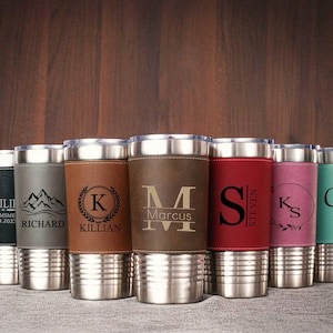 Puede incluir: Conjunto de ocho vasos de acero inoxidable personalizados con envolturas de imitaci&oacute;n de cuero. Cada vaso presenta un nombre y un dise&ntilde;o diferente, incluyendo iniciales, monta&ntilde;as y el nombre de un novio con la fecha.