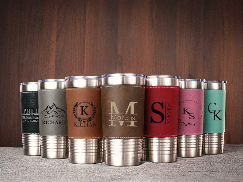 Puede incluir: Conjunto de ocho vasos de acero inoxidable personalizados con envolturas de imitaci&oacute;n de cuero. Cada vaso presenta un nombre y un dise&ntilde;o diferente, incluyendo iniciales, monta&ntilde;as y el nombre de un novio con la fecha.