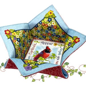 May include: A quilted fabric bowl with a red and blue floral design. The bowl features a central square with a cardinal bird illustration and the words "When Cardinals Appear, Angels are near."