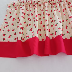 May include: A yellow and white valance with a red bottom border. The valance has a pattern of red cherries with green stems and leaves on a yellow and white striped background.