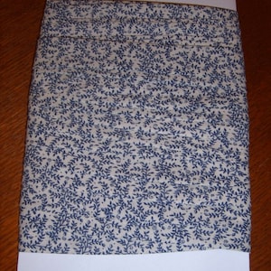 May include: A roll of white fabric with a blue floral pattern. The fabric is folded and wrapped in white paper.