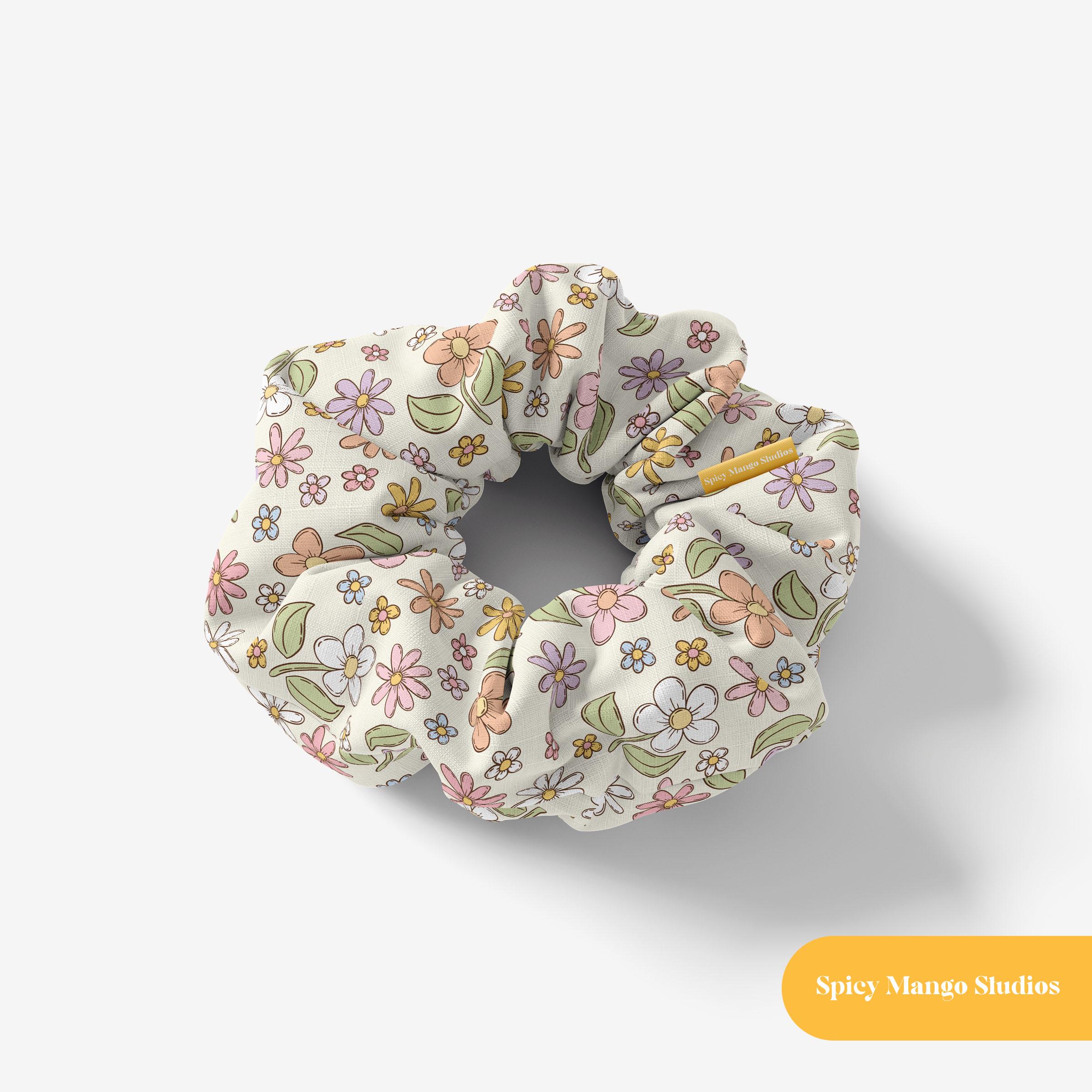 May include: A white scrunchie with a floral pattern featuring pink, yellow, and blue flowers. The scrunchie is made of soft, stretchy fabric and is perfect for holding hair in place.