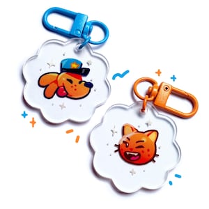 May include: Two clear acrylic keychains with cartoon animal designs. One features an orange dog in a police hat, the other an orange cat with a mischievous grin. Both have colorful metal clasps and are shaped like a flower.