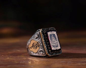 May include: A silver ring with a black stone and intricate engravings. The stone features Arabic calligraphy in gold.