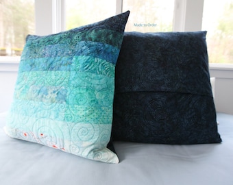 May include: Two decorative pillows, one with a blue and green ombre pattern and the other with a dark blue swirl pattern. The text "Made to Order" is visible on the pillow.