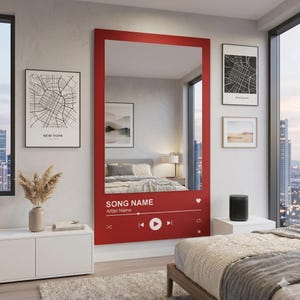 Könnte beinhalten: Ein großer rot gerahmter Spiegel mit einem Musikplayer-Oberflächendesign. Der Spiegel trägt die Aufschrift "SONG NAME" und "Artist Name". Der Spiegel befindet sich in einem Schlafzimmer mit Stadtkartenkunst und einer weißen Kommode.