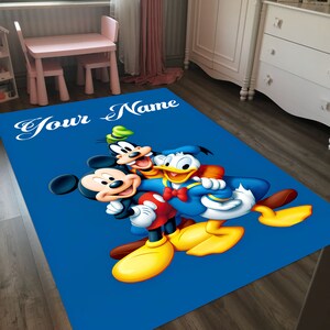 May include: A blue rug with a cartoon image of Mickey Mouse, Donald Duck, and Goofy. The rug has the text 'Your Name' at the top.