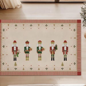 Puede incluir: Alfombra navideña rectangular beige con cinco figuras de cascanueces coloridas. Los cascanueces visten uniformes rojos, verdes y dorados, sosteniendo varios objetos festivos. La alfombra tiene un borde a rayas rojas y blancas.