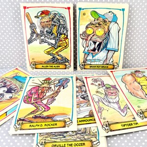 May include: A collection of rectangular trading cards featuring colorful, grotesque cartoon illustrations of baseball-themed characters. Each card displays a unique creature with a nameplate at the bottom, including Allen the Alien, Brain Rot Bruce, Ralph D. Rocker, Tiptoer Tim, Rightey W, and Orville the Oozer.