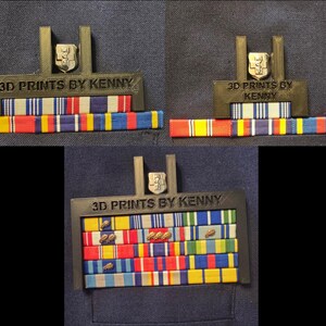 May include: A black 3D-printed display frame with the text "3D PRINTS BY KENNY" holds military ribbons. A silver emblem is at the top. The ribbons are in various colours, including red, yellow, blue, and white.