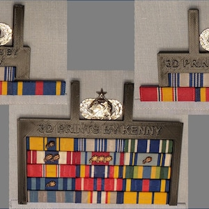 May include: A display of military ribbons and medals, with the text "3D PRINTS BY KENNY" visible. The ribbons are in various colours, including red, yellow, blue, and white. A silver emblem with a star is at the top.