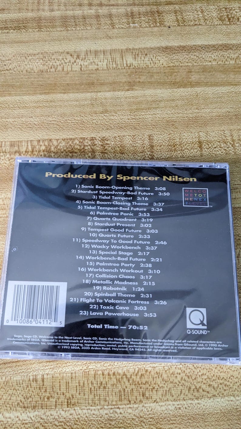 May include: A compact disc case featuring the album "Sonic CD" produced by Spencer Nilsen. The cover displays a tracklist with song titles like "Stardust Speedway" and "Palmtree Panic". The disc has a total runtime of 70:52.