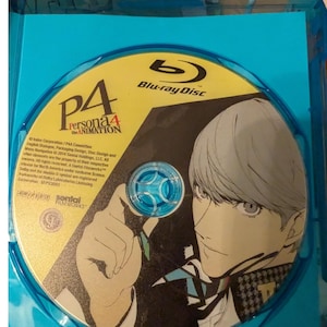 May include: A Blu-ray disc for Persona 4 The Animation housed in a blue plastic case. The disc features a yellow and black graphic of an anime character with light hair, the P4 Persona 4 The Animation logo, and the Sentai Filmworks company logo.