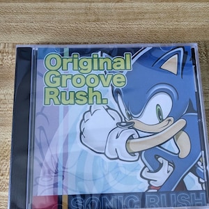 May include: A white ceramic mug with a black handle and the text "But First, Coffee" in a bold, black font. The mug is set against a blurred background, suggesting a cozy setting.