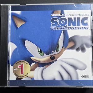 May include: A CD case featuring the Sonic the Hedgehog Vol. 1 Original Soundtrack. The cover art showcases a blue Sonic character with white gloves and green eyes. The text "SONIC THE HEDGEHOG" is prominently displayed.