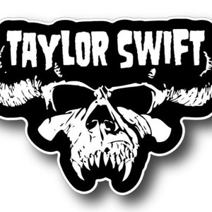 May include: Black and white sticker with a skull and horns. The text "TAYLOR SWIFT" is above the skull.