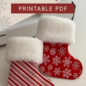Peut inclure: Deux bas de Noël avec des bordures en fausse fourrure blanche. L'un est rouge avec des flocons de neige blancs, l'autre est à rayures rouges et blanches. L'image contient le texte "Christmas Stocking Pattern & Sewing Guide PRINTABLE PDF."