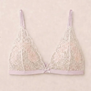 May include: A PDF sewing pattern for the Sandra Bra, featuring sizes 30-48, cups A-D, for A4 or letter printing at 100% scale. The image displays a light lavender bralette with delicate white floral lace overlay and a small center bow detail.