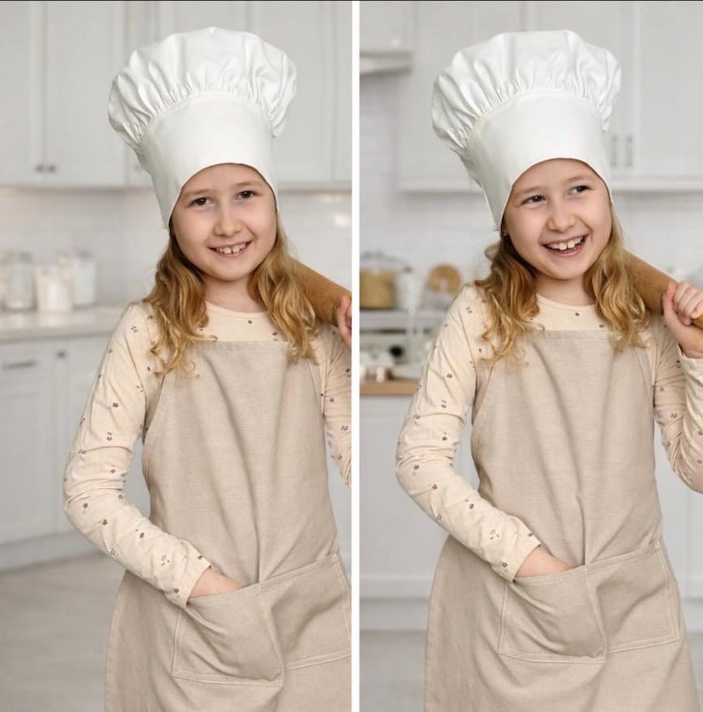 May include: A white chef hat with a pleated crown and a wide band, paired with a beige apron featuring two front pockets, worn over a long-sleeved cream shirt with a subtle pattern. The ensemble is designed for cooking and baking activities.