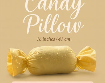 Pode incluir: Uma almofada amarela em forma de doce, com cerca de 41 cm de comprimento, com detalhes brilhantes. A almofada tem extremidades de tecido torcidas. O texto na imagem diz "Sweet Candy Pillow" e "PDF Sewing Pattern".