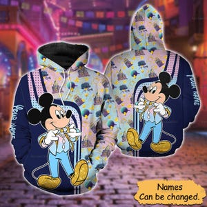 Puede incluir: Una sudadera con capucha con un patrón repetitivo de castillos y globos sobre un fondo azul claro. El frente y la espalda muestran un gráfico grande de Mickey Mouse con un traje azul claro y zapatos dorados. El texto YOUR NAME está impreso.