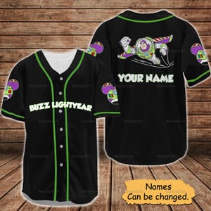 May include: Black baseball jersey featuring Buzz Lightyear graphics. The jersey has a white collar and buttons, with green trim and the words "BUZZ LIGHTYEAR" across the chest. The back displays "YOUR NAME" and a Buzz Lightyear graphic. The text "Names Can be changed" is also visible.