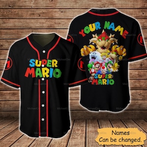 May include: Black baseball jersey featuring the text "SUPER MARIO" in colorful letters on the front. The back displays "YOUR NAME" above a graphic of Mario characters. Red trim accents the collar, sleeves, and button placket.