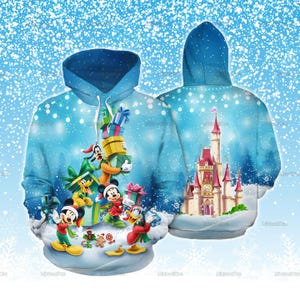 Puede incluir: Una sudadera con capucha azul que presenta una escena invernal con Mickey Mouse, Minnie Mouse, Goofy, Pluto y el Pato Donald sosteniendo regalos de Navidad. La parte trasera muestra un gran castillo con torres rojas sobre un fondo azul nevado.