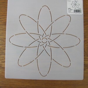 May include: A light gray plastic stencil featuring a stylized atom design. The atom design has a central circle with curved lines extending outwards. The stencil has two hanging holes at the top and a product label in the upper right corner.
