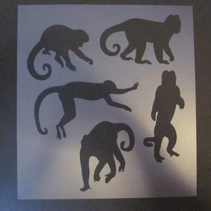 May include: A stencil with five monkey silhouettes. The monkeys are in various poses, including sitting, standing, and swinging from a branch. The stencil is made of a thin, flexible material and is designed for use with paint or other mediums.