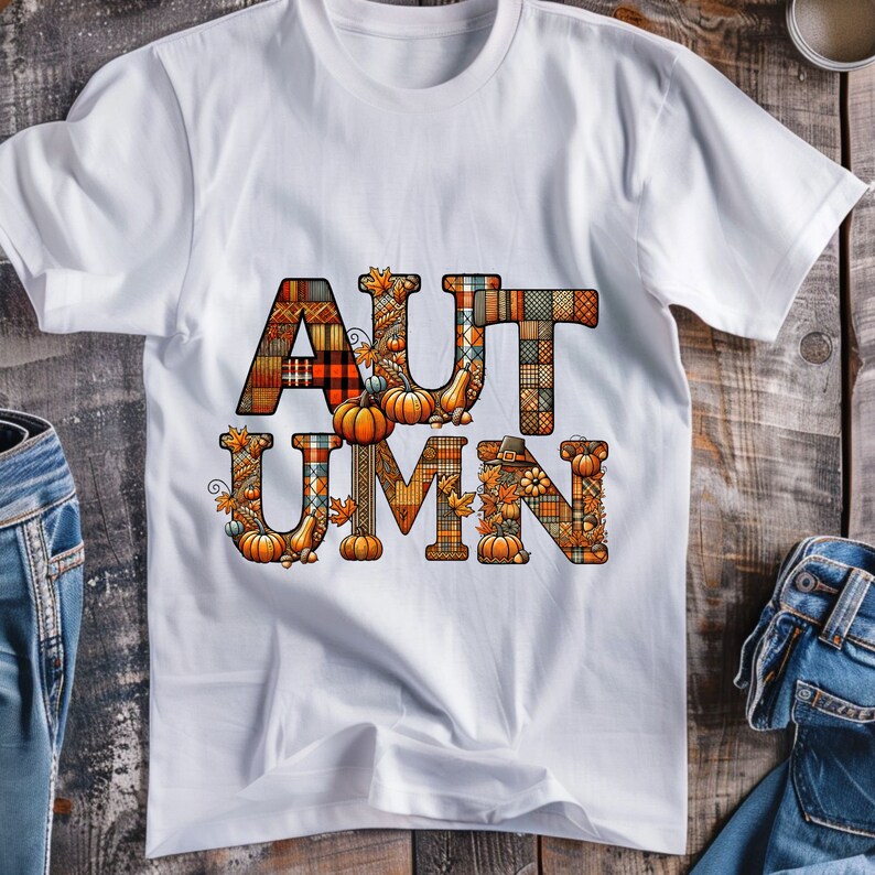 Pode incluir: Camiseta branca com a palavra "AUTUMN" escrita em letras grandes e coloridas. As letras s&atilde;o feitas de um mosaico de diferentes tecidos, incluindo padr&otilde;es de xadrez, flores e paisley. As letras s&atilde;o decoradas com pequenas ab&oacute;boras, folhas e bolotas.