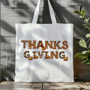 Pode incluir: Sacola branca de tecido com as palavras "THANKSGIVING" escritas em letras xadrez laranja, marrom e amarelo com pequenas ab&oacute;boras e folhas nas letras.